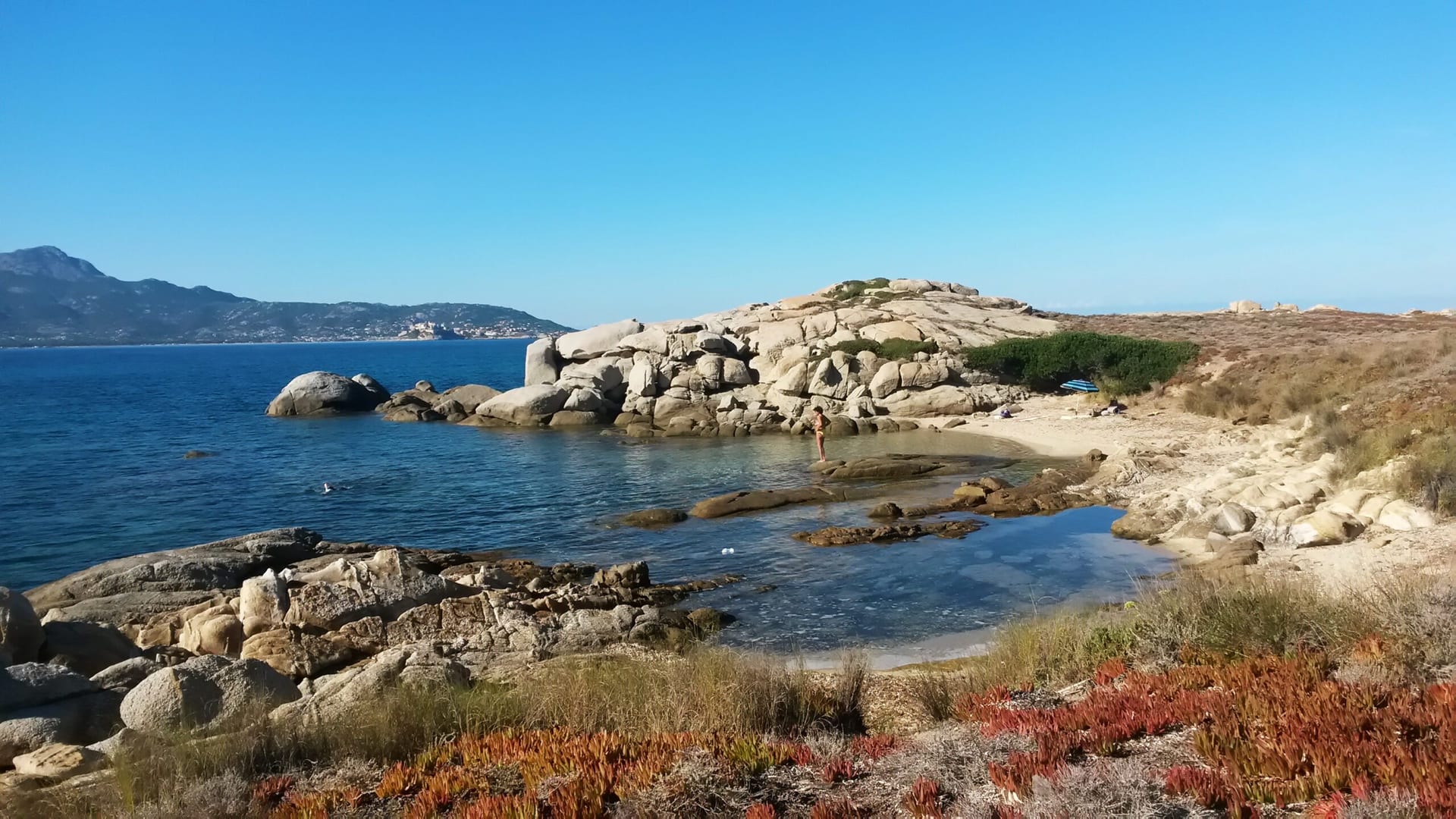 Felsbucht der Balagne mit kristallklarem Wasser und Bergpanorama