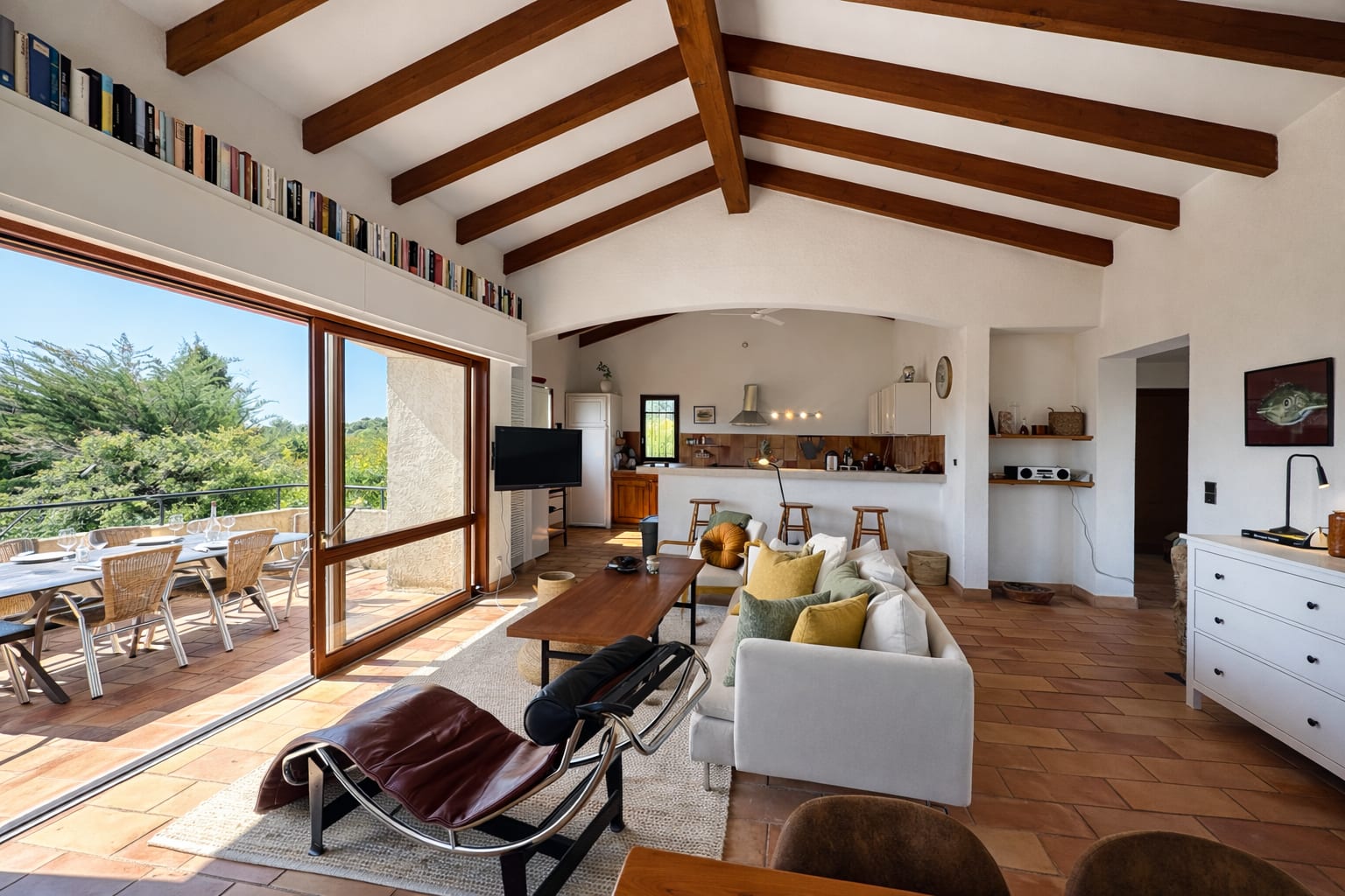 Wohnzimmer mit Sofa, Esstresen und offener Tür zur Terrasse mit Bergblick